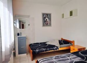 A bedroom with a bed, a bedside table, a dresser, a mirror, and a wall-mounted picture.