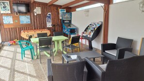 A room with a pool table, chairs, a foosball table, and a children's play area.