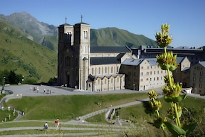 A church with a bell tower, a large building with multiple windows, and a grassy area with a statue.