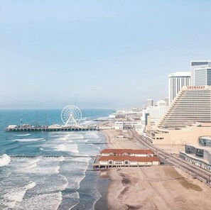 A coastal cityscape with a prominent Ferris wheel, a pier extending into the ocean, and a building labeled 'SHOWBOAT' with a sloped roof. - 2 bedroom apt, with water park, on the Boardwalk (Atlantic City)