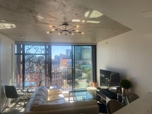 Un salon moderne doté d’une grande baie vitrée, d’un ventilateur de plafond, d’un canapé, d’un téléviseur et d’un coin repas.