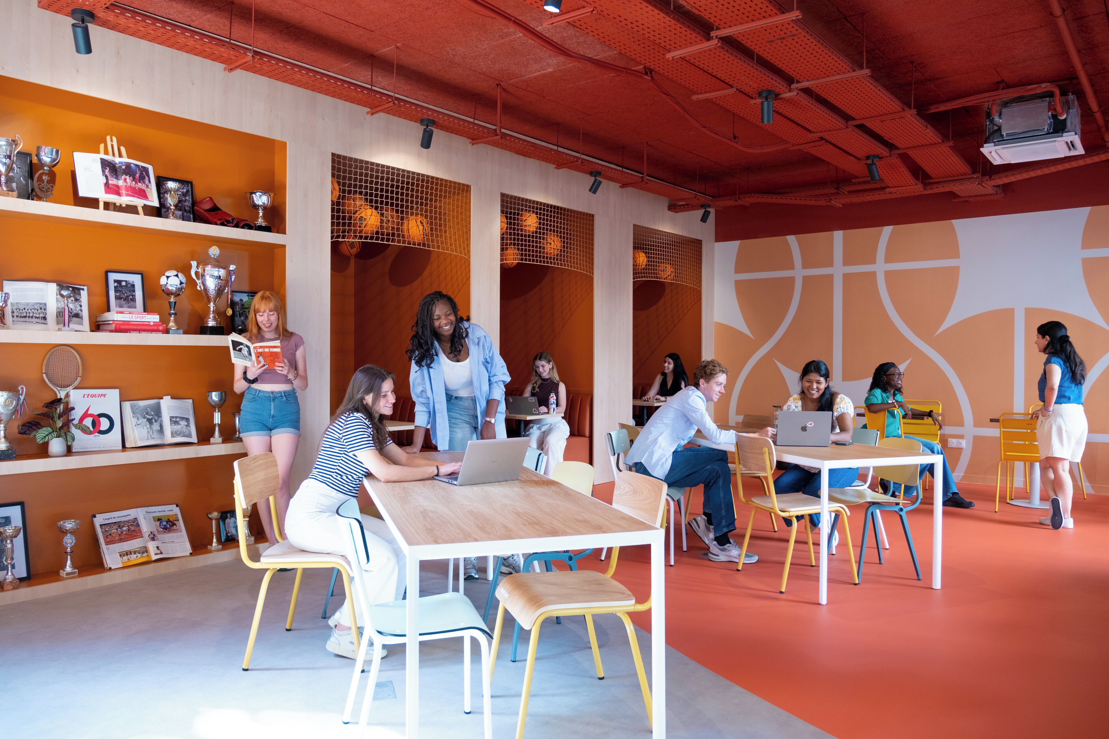 Een moderne co-workingruimte met gemeenschappelijke tafels, individuele werkplekken en een levendig kleurenschema in oranje en wit.