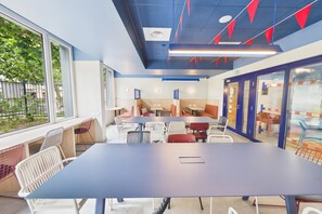 Una sala de conferencias moderna con una gran mesa y sillas, ventanas amplias y vistas a zonas verdes exteriores.