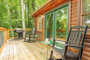 A wooden cabin with a deck, outdoor seating, and a grill. - *Relaxing 2BD w/ Hot Tub | Fireplace + Near TOWN* (Sevierville)
