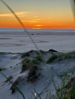 A beach with sand dunes and a sunset.