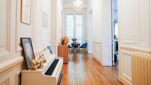 A hallway with a piano, framed pictures, a chandelier, and a dining area with a table and chairs. - Charming mansion with terrace - Jardin Public (sleeps 8) (Bordeaux)