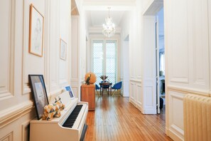 A hallway with a piano, framed pictures, a chandelier, and a dining area with a table and chairs. - Charming mansion with terrace - Jardin Public (sleeps 8) (Bordeaux)