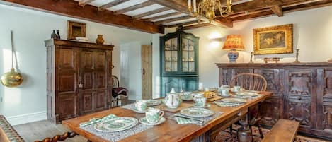 Comedor con mesa de madera para cuatro personas, lámpara de araña y decoración tradicional.