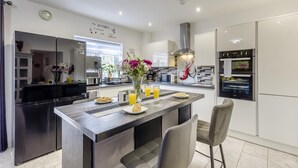 Una cocina moderna con una isla central, electrodomésticos integrados y un letrero decorativo en la pared.