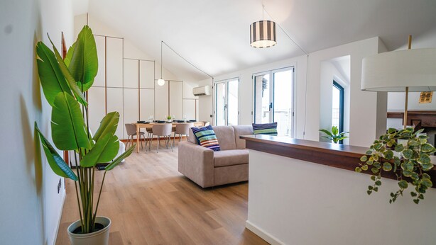 Ein moderner Wohnraum mit Essbereich, einer Couch und einer Kücheninsel.