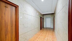 A hallway with marble walls and wooden flooring, leading to a door marked '101'. - Classic Hotel Gandimaisamma (Hyderabad)