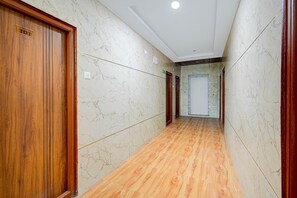 A hallway with marble walls and wooden flooring, leading to a door marked '101'. - Classic Hotel Gandimaisamma (Hyderabad)