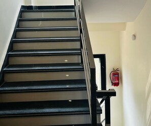 Eine Treppe mit schwarzen Stufen und einem Metallgeländer.