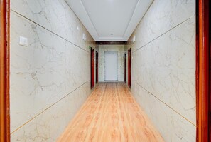 A hallway with marble walls and wooden flooring, leading to a door at the end. - Classic Hotel Gandimaisamma (Hyderabad)