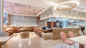 Una cocina moderna con una isla central, electrodomésticos integrados y un alto techo con iluminación decorativa.