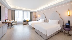 Habitación de hotel con dos camas, un escritorio, una silla, un sofá, una lámpara y un televisor.
