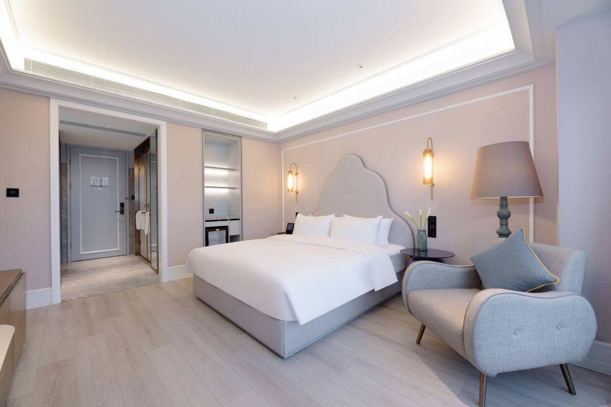 Una habitación de hotel moderna con una cama grande, mesitas de noche, una silla y un escritorio.