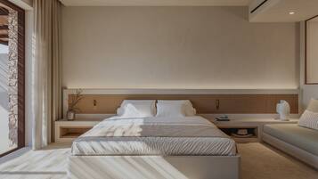 A modern bedroom with a large bed, bedside tables, a sofa, and a large window.