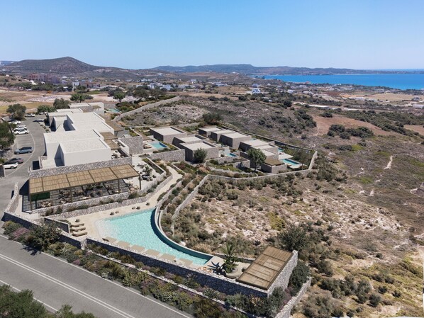 A resort with multiple buildings, a swimming pool, and a view of the sea. - ONERO (Milos)