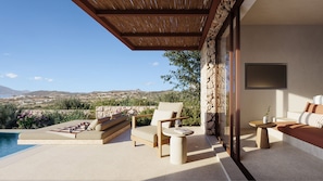 A modern outdoor lounge area with a pool, seating, and a view of the landscape. - ONERO (Milos)