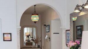 Un couloir avec une console en bois, un miroir et une lampe suspendue.