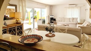 Un salon avec un canapé blanc, une table à manger agrémentée d’un vase décoratif et un téléviseur.