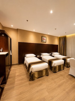 A hotel room with three beds, a wooden wardrobe, a desk, and a picture on the wall. - Premium Land 1 (Makkah)