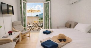 Ein Hotelzimmer mit Bett, Sessel, kleinem Tisch und einem Balkon mit Tisch und Sonnenschirm.