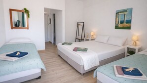 Ein Hotelzimmer mit zwei Betten, einem Spiegel, einem Gemälde und einem Nachttisch mit einer Lampe.