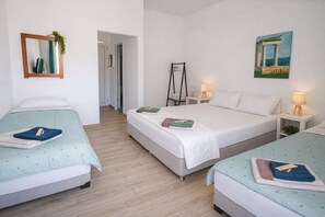 Ein Hotelzimmer mit zwei Betten, einem Spiegel, einem Gemälde und einem Nachttisch mit einer Lampe.