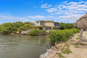 A two-story house with a balcony, located near a body of water with vegetation. - The Peninsular House – Private Waterfront Paradise (Marathon)