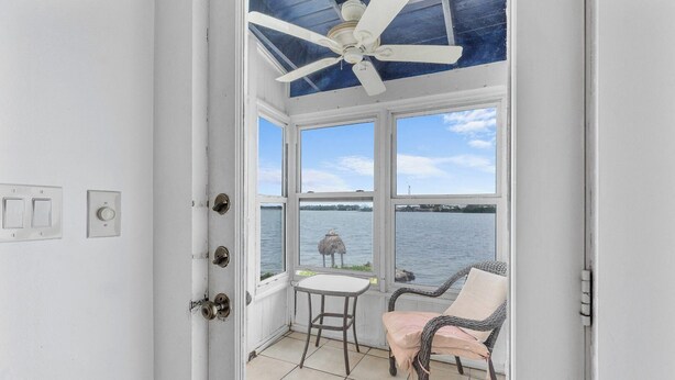 A room with a ceiling fan, a view of the water, a table, and two chairs. - The Peninsular House – Private Waterfront Paradise (Marathon)