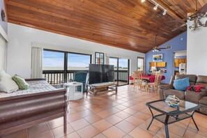 A spacious living area with a large TV, wooden ceiling, and a balcony with a view. - The Peninsular House – Private Waterfront Paradise (Marathon)