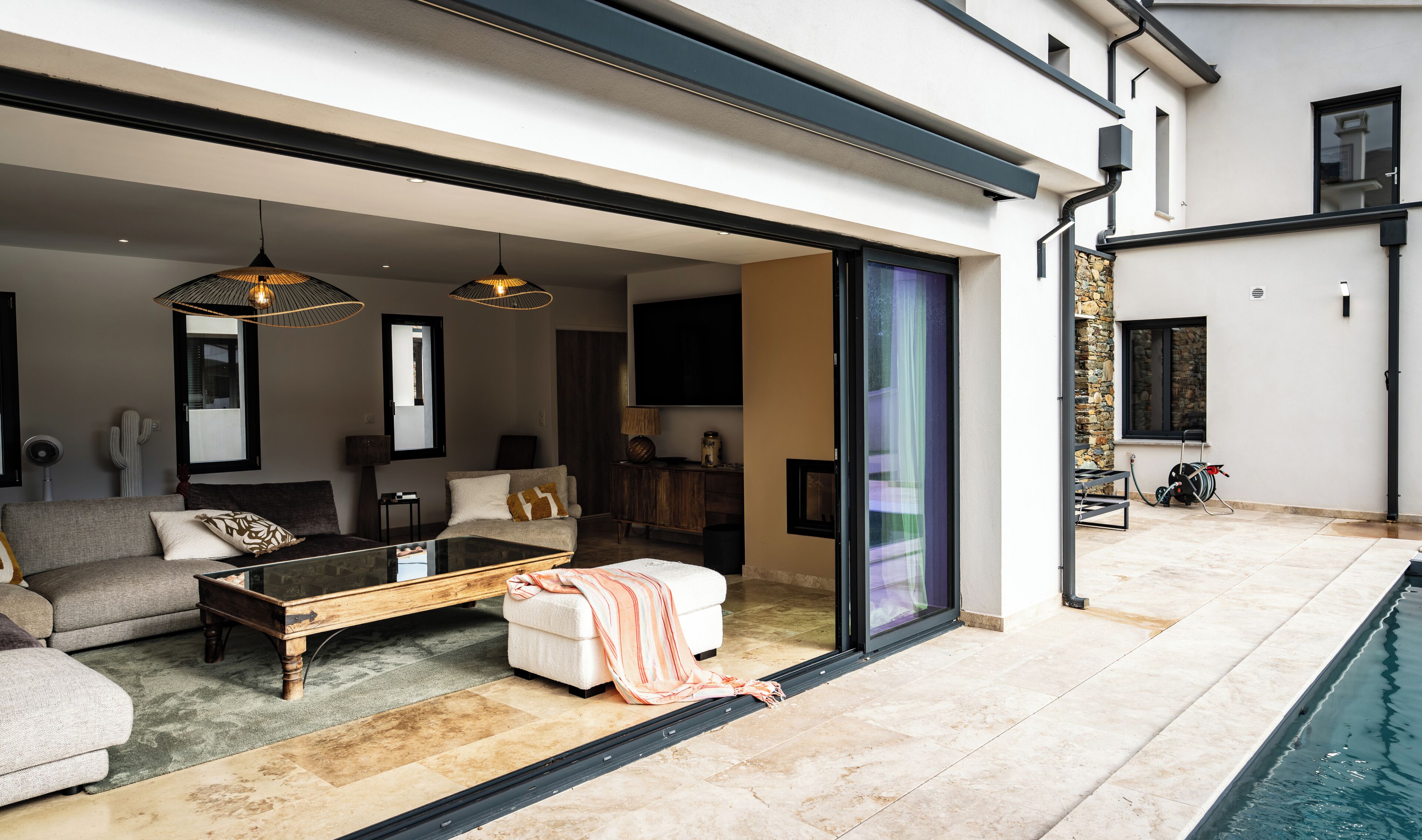 A modern living room with a glass door leading to a pool area.