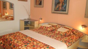 Un dormitorio con cama, mesita de noche, espejo y decoración en la pared.
