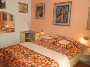 Ein Schlafzimmer mit Bett, Nachttisch, Spiegel und Wandbildern.