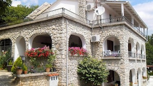 Un edificio de piedra con varios balcones y ventanas arqueadas, algunas con plantas en macetas.