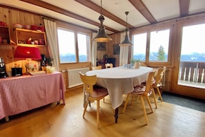 A dining area with a round table, wooden chairs, and a red checkered tablecloth.