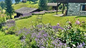 Uma casa rústica com parede de pedra, deck de madeira e vista para montanhas.