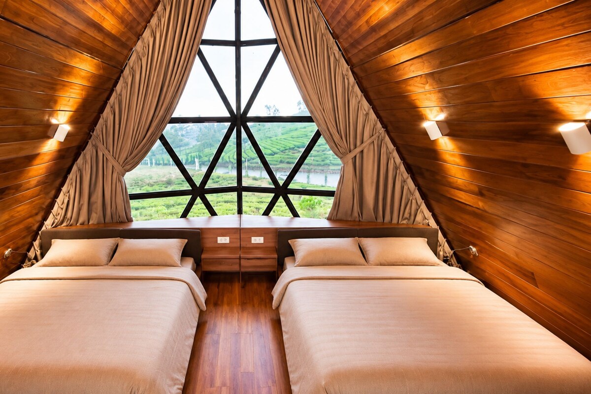 Una habitación con paredes de madera, un ventanal grande, dos camas y una mesita.