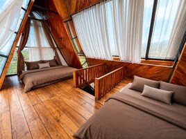 Um quarto acolhedor com painéis de madeira, uma cama, um sofá e janela com vista para uma paisagem exuberante.