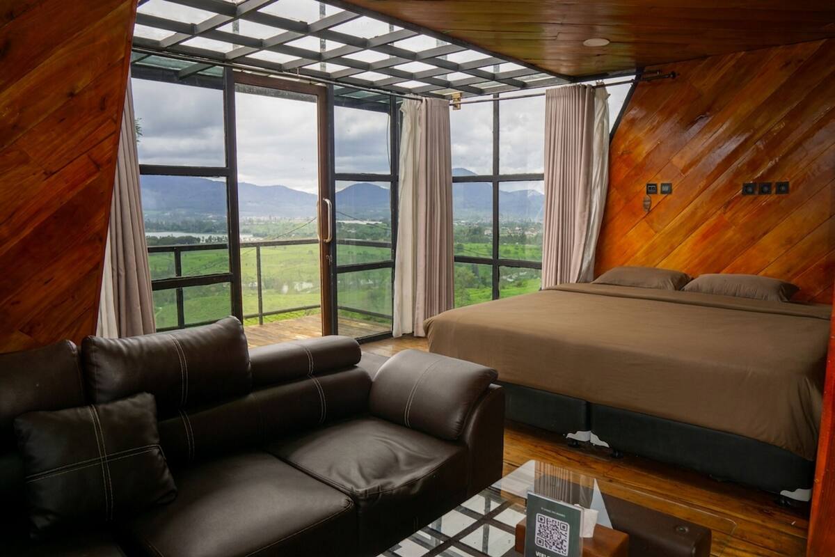 A room with a large bed, a sofa, and a glass table with a QR code.
