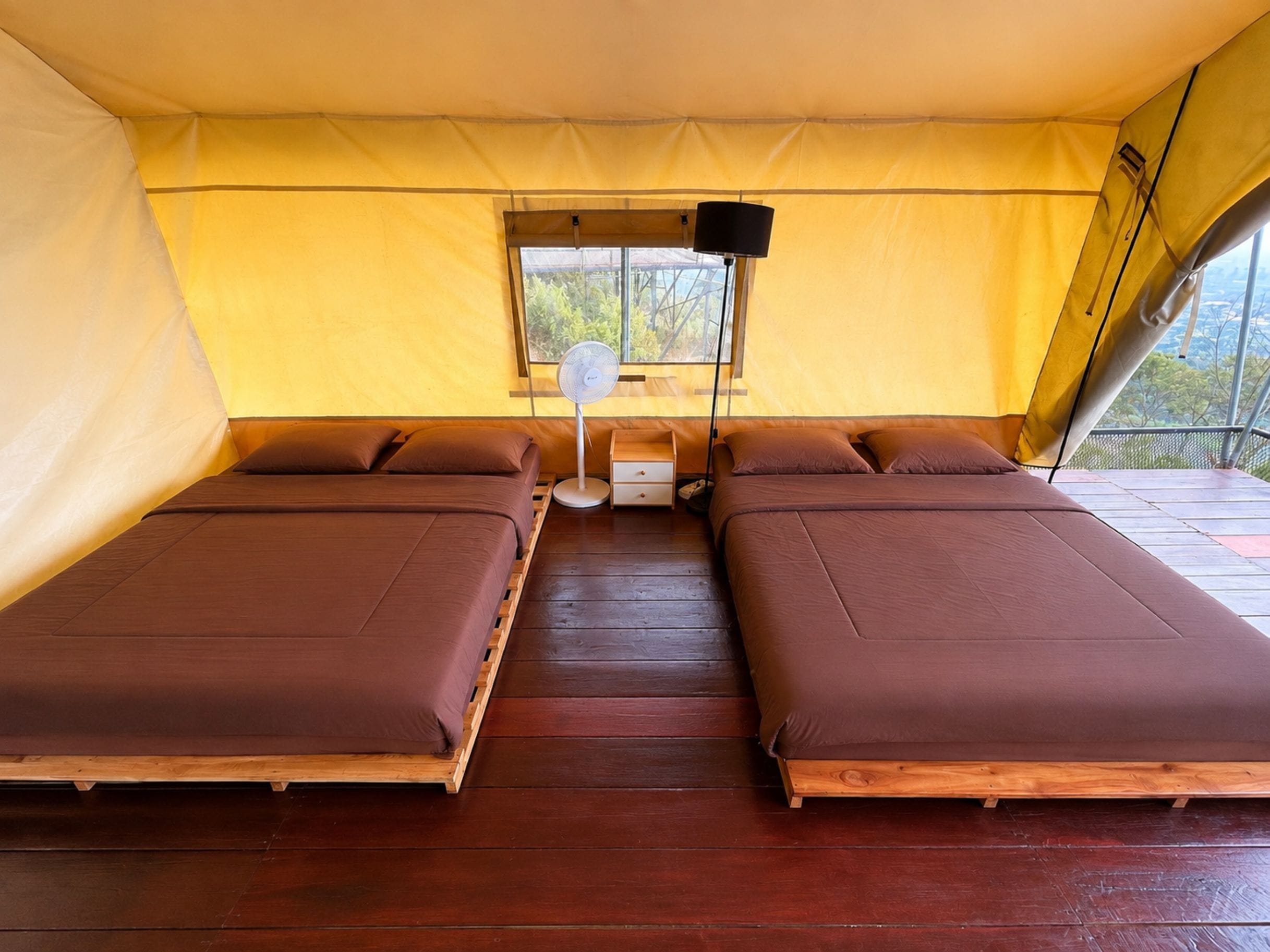 Una tenda amb dos llits, una finestra i un ventilador.