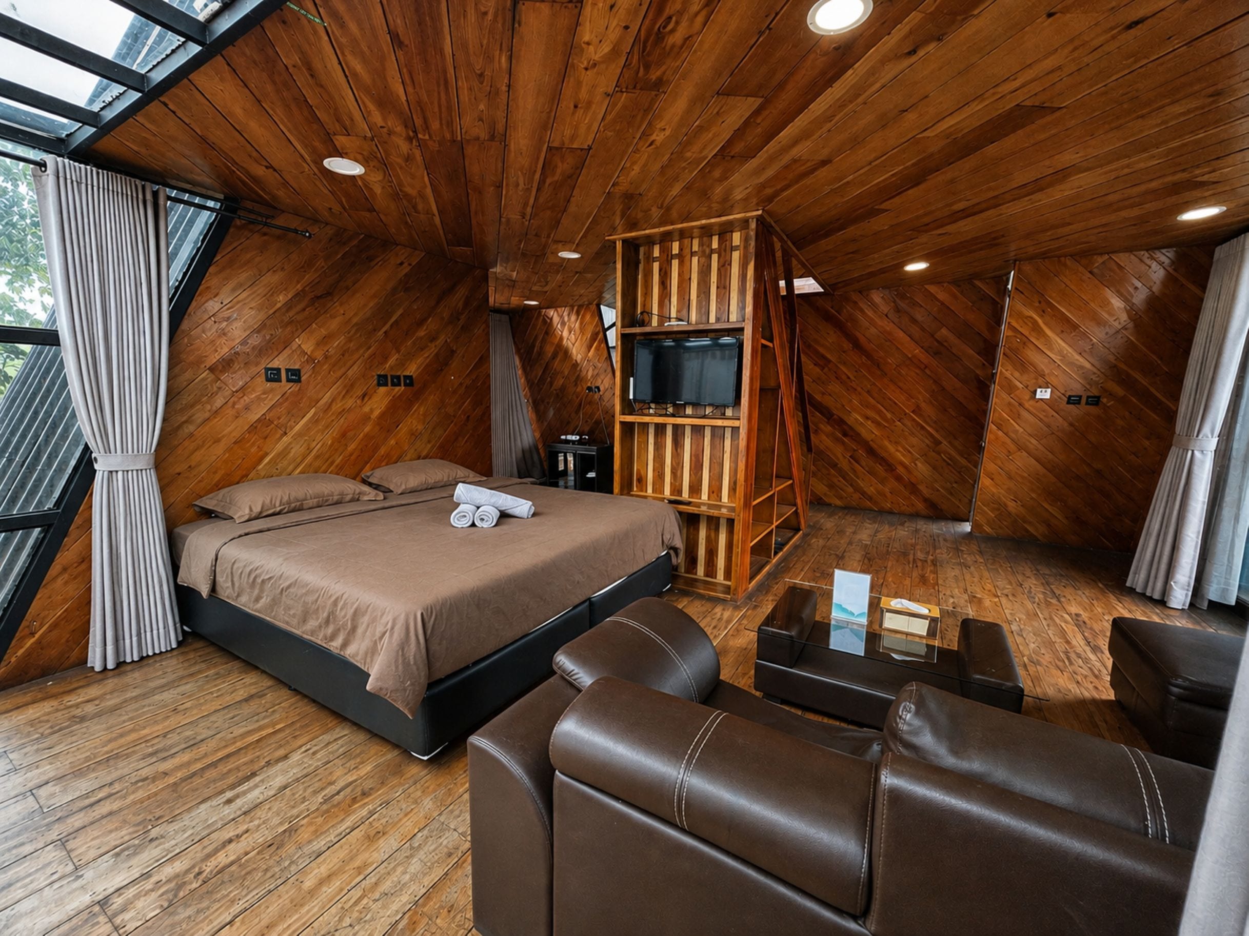 A bedroom with a bed, a TV, and a seating area.