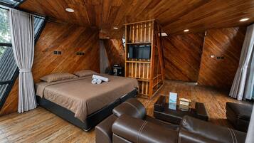 A bedroom with a bed, a TV, and a seating area.