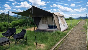 Una carpa montada en un área verde con un camino pavimentado cerca.