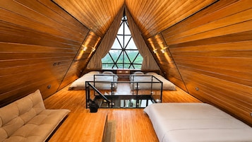 Un dormitorio acogedor en el ático con paredes de madera, techo de cristal y cama con vistas al exterior.
