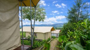 Un camping con tiendas de campaña, un camino pavimentado y vistas a montañas distantes.
