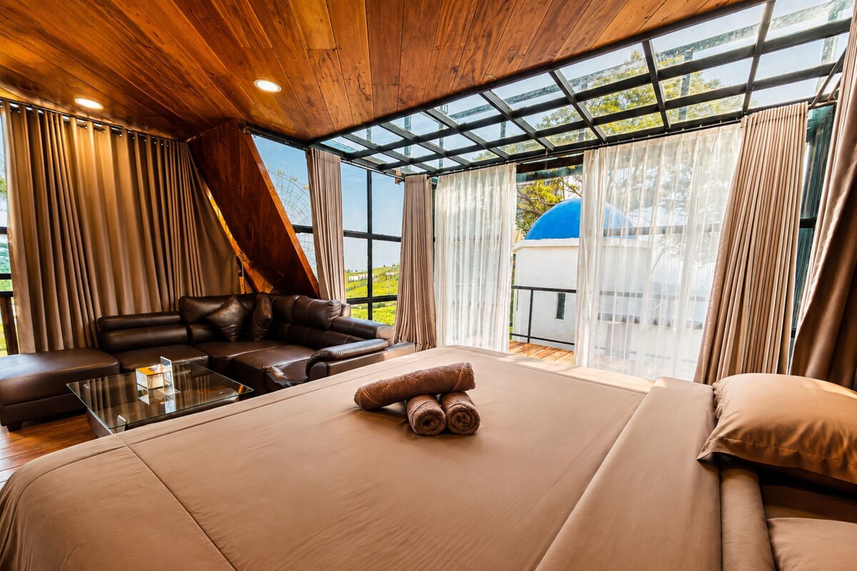 Un dormitorio moderno con una cama grande, un sofá de cuero y una mesa de centro de vidrio.