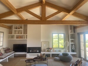 Ein geräumiges Wohnzimmer mit hoher Decke, Einbauschränken, einem Kamin und einem großen Fenster.